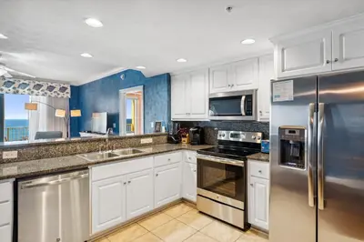 a kitchen with white cabinets and stainless steel appliances at Treasure Island #1207 in Panama City Beach