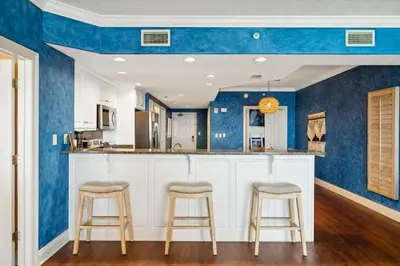 a kitchen with blue walls and bar stools at Treasure Island #1207 in Panama City Beach