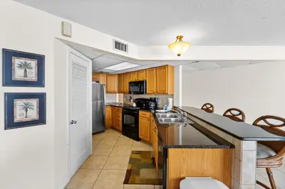 a kitchen with wooden cabinets and a stainless steel appliances at Aquavista Condominiums #205-W by Book That Condo in Panama City Beach