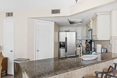 a kitchen with white cabinets and a stainless steel refrigerator at Aquavista Condominiums #204-W by Book That Condo in Panama City Beach