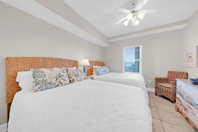a bedroom with a bed and a couch and a fan at Celadon 302 in Panama City Beach