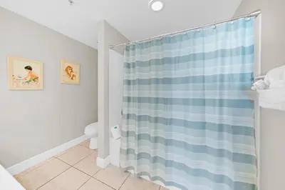 a bathroom with a shower with a blue and white shower curtain at Celadon 302 in Panama City Beach