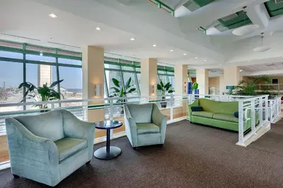 a lobby with two chairs and a table and windows at Emerald Beach Resort 2235 in Panama City Beach