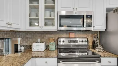 a kitchen with white cabinets and a stove and a microwave at Villas at Seagrove B101 in Santa Rosa Beach