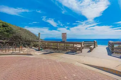two benches sitting on a boardwalk near the ocean at The Ocean Pearl in Santa Rosa Beach
