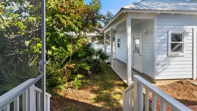 a white house with a porch and a white fence at The Ocean Pearl in Santa Rosa Beach