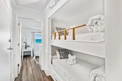 a white room with two bunk beds and a couch at The Summit 518 in Panama City Beach