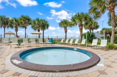 a swimming pool with chairs and palm trees at The Summit 518 in Panama City Beach