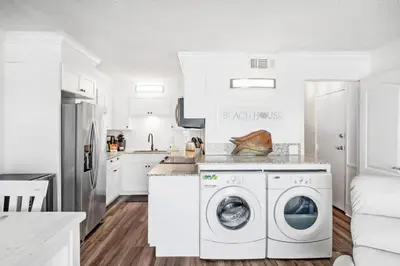 a white kitchen with a washer and dryer in it at The Summit 518 in Panama City Beach