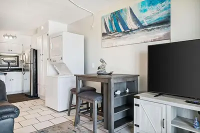a living room with a table and a flat screen tv at The Summit 725 in Panama City Beach