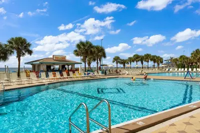 a large swimming pool with palm trees and a beach at The Summit 725 in Panama City Beach
