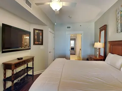 a bedroom with a large bed and a flat screen tv at Grand Panama Beach Resort - The Grand #201 - Sunny Shores in Panama City Beach