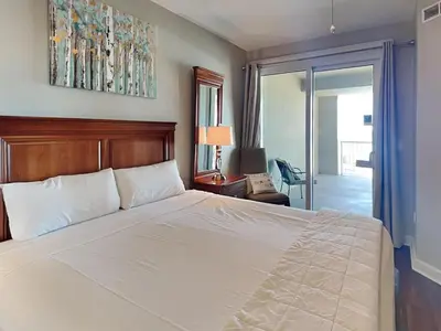 a bedroom with a large white bed and a sliding glass door at Grand Panama Beach Resort - The Grand #201 - Sunny Shores in Panama City Beach
