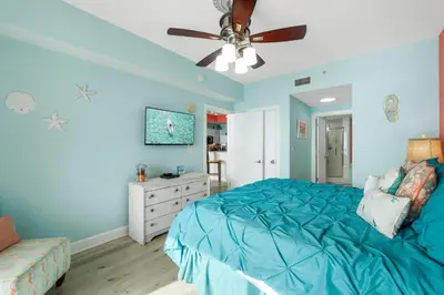 a blue bedroom with a bed and a ceiling fan at Once Upon A Tide in Panama City Beach
