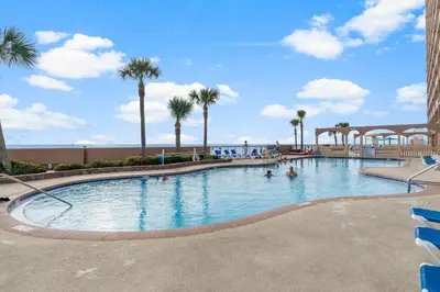 a pool at a resort with palm trees and people in it at Once Upon A Tide in Panama City Beach
