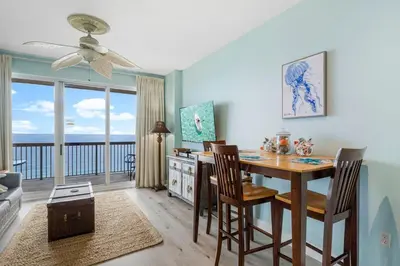 a dining room with a table and chairs with a view of the ocean at Once Upon A Tide in Panama City Beach
