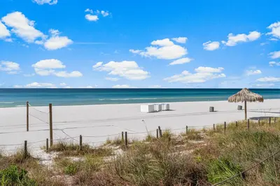 a beach with an umbrella and chairs and the ocean at Spectacular 3BD Beachfront Condo! Spacious! by Dolce Vita Getaways PCB in Panama City Beach