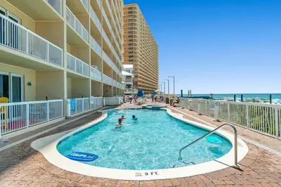 a swimming pool at a resort with the ocean in the background at Seychelles #703 by Nautical Properties in Panama City Beach