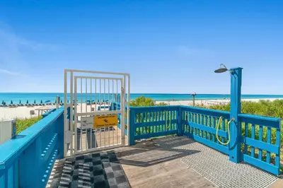 a blue gate at the beach with the ocean in the background at Seychelles #703 by Nautical Properties in Panama City Beach