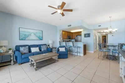 a living room with a blue couch and a kitchen at Seychelles #703 by Nautical Properties in Panama City Beach