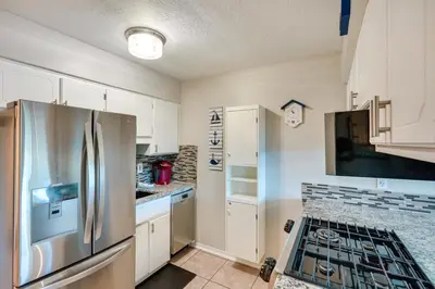a kitchen with white cabinets and a stainless steel refrigerator at Walk to Beach and Restaurants PCB Resort Condo! in Panama City Beach