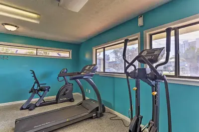 a gym with three tread machines in a room with blue walls at Walk to Beach and Restaurants PCB Resort Condo! in Panama City Beach