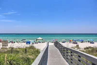 a wooden boardwalk leading to a beach with umbrellas at Walk to Beach and Restaurants PCB Resort Condo! in Panama City Beach