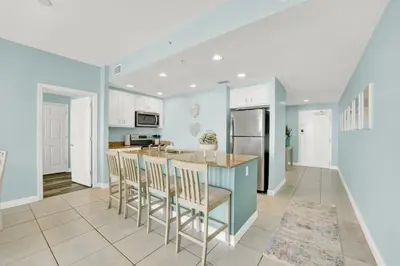a kitchen with a blue island with bar stools at Sterling Reef 1802B in Panama City Beach