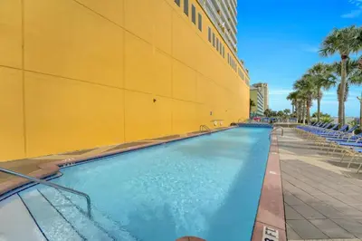 a large swimming pool next to a yellow building at Sterling Reef 1802B in Panama City Beach