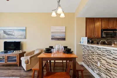 a living room with a table and a kitchen at Seychelles 205 in Panama City Beach