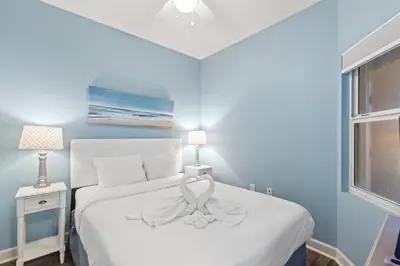 a bedroom with a white bed with a bow on it at Seychelles 205 in Panama City Beach