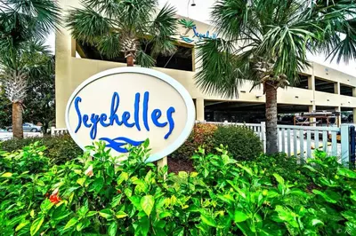 a sign in front of a building with palm trees at Seychelles 205 in Panama City Beach