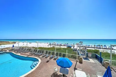 a pool with chairs and umbrellas and the beach at Seychelles 205 in Panama City Beach