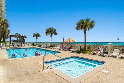 a swimming pool with people sitting in chairs next to the ocean at Ocean Villa 1104 in Panama City Beach