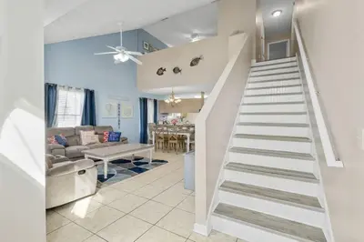 a white staircase in a living room with a couch at 126 Seagrass Way in Panama City Beach