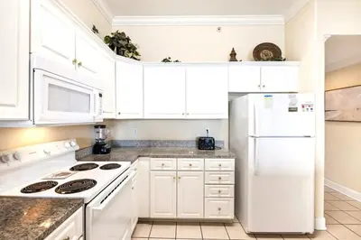 a kitchen with white cabinets and a white refrigerator at Ocean Villa 2101 in Panama City Beach