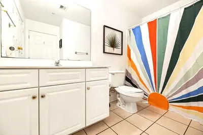 a bathroom with a toilet and a colorful shower curtain at Ocean Villa 2101 in Panama City Beach