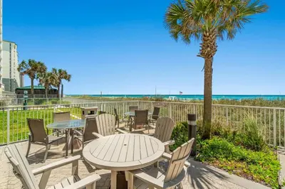 a patio with a table and chairs and a palm tree at Ocean Villa 2101 in Panama City Beach