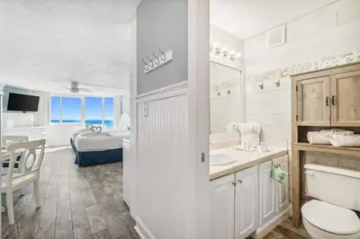a bathroom with a sink and a toilet and a bedroom at Top Of The Gulf 613 in Panama City Beach