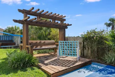 a wooden deck with a bench and a pergola at Top Of The Gulf 613 in Panama City Beach