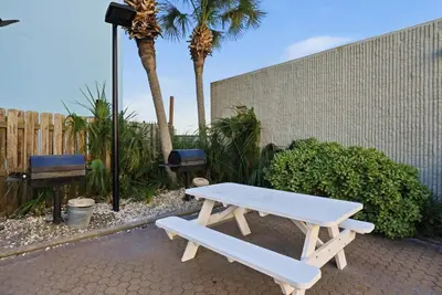 a white picnic table sitting next to a fence at Top Of The Gulf 613 in Panama City Beach
