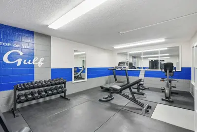 a gym with dumbbells and weights in a room at Top Of The Gulf 613 in Panama City Beach