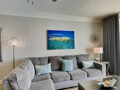 a living room with a gray couch and a table at Majestic Beach Towers I #1503 in Panama City Beach