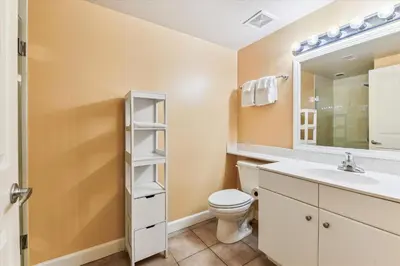 a bathroom with a toilet and a sink and a mirror at Shores of Panama 1427 condo in Panama City Beach