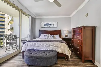 a bedroom with a bed and a dresser and a balcony at Shores of Panama 723 condo in Panama City Beach