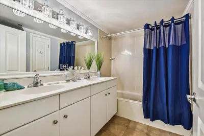 a bathroom with a sink and a blue shower curtain at Shores of Panama 723 condo in Panama City Beach