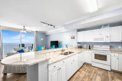 a kitchen with white cabinets and a view of the ocean at Beautiful Beach front condo! - Tidewater 1804 in Panama City Beach