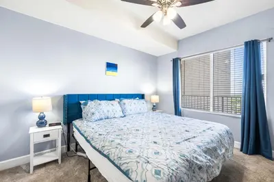 a bedroom with a blue bed and a window at Beautiful Beach front condo! - Tidewater 1804 in Panama City Beach