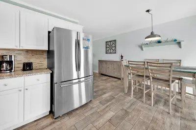 a kitchen with a stainless steel refrigerator and a table at All Decked Out on PCB in Panama City Beach