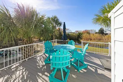 a patio with blue chairs and an umbrella on a deck at All Decked Out on PCB in Panama City Beach